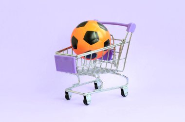 Menekşe üzerinde alışveriş arabası turuncu futbol topu. Spor malzemeleri satan kavramı, spor predictions maçlar, spor bahisleri