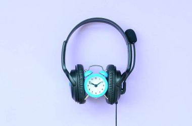 Menekşe arka plan üzerinde siyah kulaklıklarla Retro çalar saat. Müzik dinleme süresi kavramı