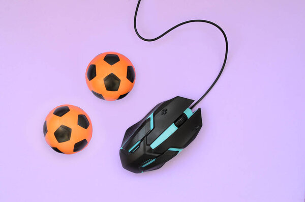 Два футбольных мяча с компьютерной мышью на фиолетовом фоне. Концепция видеоигр, электронных видов спорта, ставок на спорт и онлайн азартных игр
