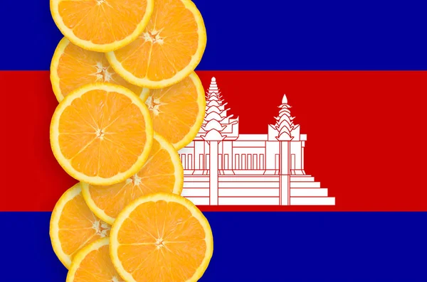 Cambodia flag and vertical row of orange citrus fruit slices. Concept of growing as well as import and export of citrus fruits