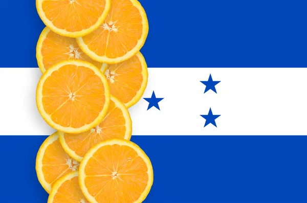 ホンジュラスの国旗とオレンジの柑橘系フルーツのスライスの縦の列 柑橘類の輸出入だけでなく 成長の概念 — ストック写真