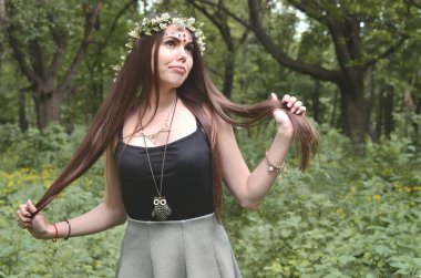 Çiçek çelenk başında ve alnındaki parlak süsler ile duygusal bir genç kız portresi. Şirin esmer güzel bir gün gündüz gelişen bir ormanda poz