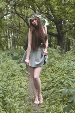 Güzel bir genç esmer koyu kahverengi gözleri ve büyük dudaklar ile Avrupa görünüm bir orman resim. Kızın üzerinde kafasını onun alnında parlak süslemeleri çiçek çelenk takarak