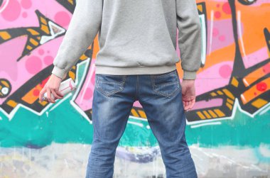 Gri kapüşonlu bir genç grafiti sanatçısı bir duvara yağmurlu havalarda pembe ve yeşil renklerde onun graffiti ile duvara görünüyor. Sokak sanatı kavramı
