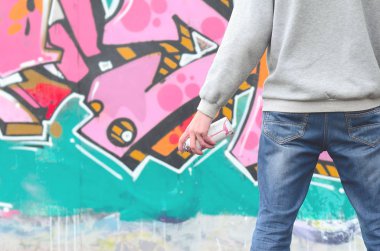 Gri kapüşonlu bir genç grafiti sanatçısı bir duvara yağmurlu havalarda pembe ve yeşil renklerde onun graffiti ile duvara görünüyor. Sokak sanatı kavramı