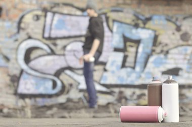 Natürmort birkaç sprey boya sprey kutular, parlak ve renkli grafiti çizim boyanmış bir tuğla duvar arka plan üzerinde kapsayan bir çatı yer alır. Sokak sanatı ile ilgili öğeler