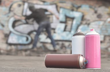 Natürmort, birkaç farklı renk üzerinde genç bir adam grafiti çizim uyguluyor duvara boya... kutularını kullanılır. Kavram sokak sanatı ve kültür gençlik Sanat Duvar Boya için