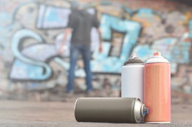 Natürmort, birkaç farklı renk üzerinde genç bir adam grafiti çizim uyguluyor duvara boya... kutularını kullanılır. Kavram sokak sanatı ve kültür gençlik Sanat Duvar Boya için