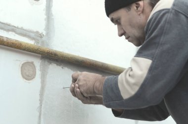 Yaşlı bir işçi sonraki delme ve bir şemsiye dübel montajı için genişletilmiş polistiren duvardaki delik oluşturur. Genişletilmiş polistiren levhalar sabitleme işlemi. İzolasyon işi