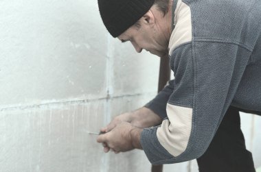 Yaşlı bir işçi sonraki delme ve bir şemsiye dübel montajı için genişletilmiş polistiren duvardaki delik oluşturur. Genişletilmiş polistiren levhalar sabitleme işlemi. İzolasyon işi