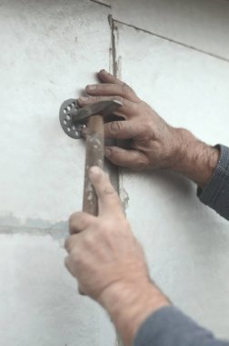 Yaşlı bir işçi Strafor duvarındaki bir plastik şemsiye bağlama içine bir dübel takunya. Genişletilmiş polistiren levhalar sabitleme işlemi. Bina cephe ısınma