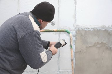 Yaşlı bir işçi bir plastik dübel takviye izleyen yüklemesi için styrofoam duvarında bir delik matkap. Delik duvara bir matkapla oluşturmak. Bina cephe Isınma