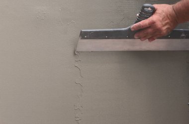 Ev yenilenen araçları sıvama duvar ile eski bir işçi elleri. Sıvacı yenilenen açık duvar ve spatula ve alçı ile köşeleri. Duvar izolasyonu. İnşaat bitirme işleri