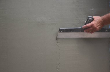 Ev yenilenen araçları sıvama duvar ile eski bir işçi elleri. Sıvacı yenilenen açık duvar ve spatula ve alçı ile köşeleri. Duvar izolasyonu. İnşaat bitirme işleri