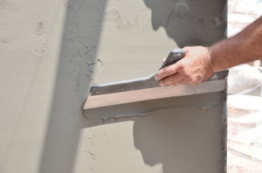 Ev yenilenen araçları sıvama duvar ile eski bir işçi elleri. Sıvacı yenilenen açık duvar ve spatula ve alçı ile köşeleri. Duvar izolasyonu. İnşaat bitirme işleri