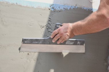 Ev yenilenen araçları sıvama duvar ile eski bir işçi elleri. Sıvacı yenilenen açık duvar ve spatula ve alçı ile köşeleri. Duvar izolasyonu. İnşaat bitirme işleri