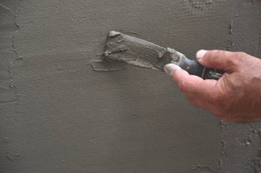Ev yenilenen araçları sıvama duvar ile eski bir işçi elleri. Sıvacı yenilenen açık duvar ve spatula ve alçı ile köşeleri. Duvar izolasyonu. İnşaat bitirme işleri