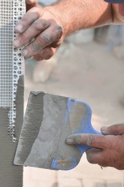 Ev yenilenen araçları sıvama duvar ile eski bir işçi elleri. Sıvacı yenilenen açık duvar ve spatula ve alçı ile köşeleri. Duvar izolasyonu. İnşaat bitirme işleri