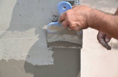 Ev yenilenen araçları sıvama duvar ile eski bir işçi elleri. Sıvacı yenilenen açık duvar ve spatula ve alçı ile köşeleri. Duvar izolasyonu. İnşaat bitirme işleri