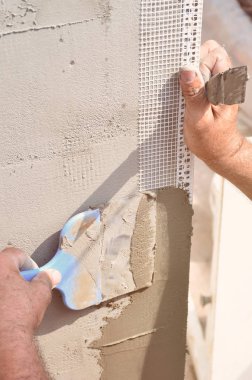 Ev yenilenen araçları sıvama duvar ile eski bir işçi elleri. Sıvacı yenilenen açık duvar ve spatula ve alçı ile köşeleri. Duvar izolasyonu. İnşaat bitirme işleri