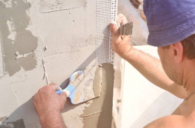Elli yaşında işçi ile duvar ev tadilatı araçları sıvama. Sıvacı yenilenen duvarlar ve spatula ve alçı ile köşeleri. Duvar mash yükleme. İnşaat bitirme işleri