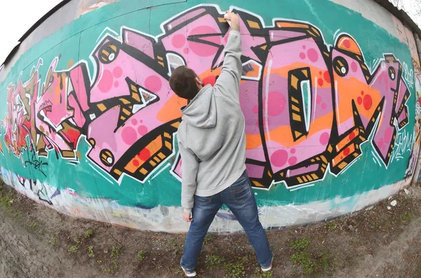 Mladý Muž Šedém Hoodie Maluje Graffiti Růžové Zelené Barvy Zeď — Stock fotografie