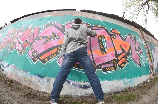 Mladý Muž Šedém Hoodie Maluje Graffiti Růžové Zelené Barvy Zeď — Stock fotografie