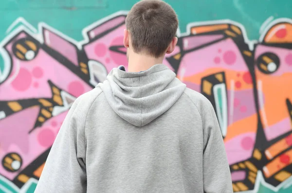 Gri kapüşonlu bir genç grafiti sanatçısı bir duvara yağmurlu havalarda pembe ve yeşil renklerde onun graffiti ile duvara görünüyor. Sokak sanatı kavramı