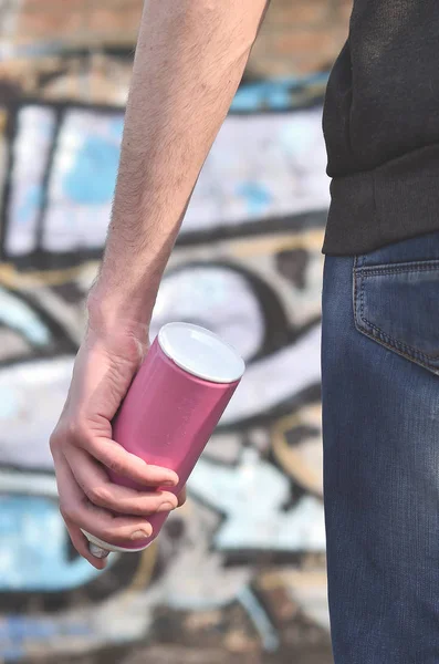 Rear view of a guy drawing a wall with aerosol paint. A photography of a graffiti artist with a spray can in his hand. Concept of street art, drawing paint on the walls