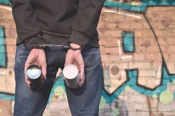 Genç bir serseri fotoğrafı polis tarafından yakalanmış ve kelepçe zincirle. Duvarları sprey boya ile boyama özelliği, şımarık bir adamın tutuklanışını. Gençlik holiganizmi ve grafiti mücadele