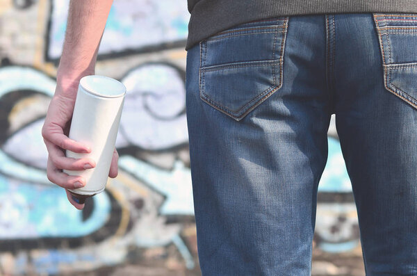 Фото хулигана, который портит государственную собственность, красит стены аэрозольной краской. Фрагмент тела молодого преступника с распылителем краски в грязной руке. Проблема повреждения имущества
