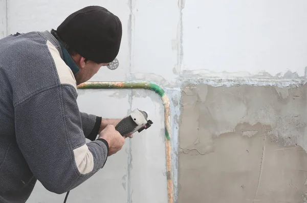 An elderly workman drills a hole in a styrofoam wall for the subsequent installation of a plastic reinforcing dowel. Creating holes in the wall with a drill. Warming of the building facade — Stock Image Elderly Workman Drills Hole Styrofoam Wall Subsequent Installation Plastic Reinforcing Royalty Free Stock Photos
