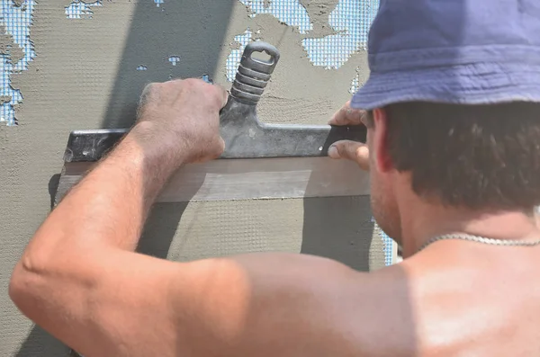 Fifty years old manual worker with wall plastering tools renovating house. Plasterer renovating walls and corners with spatula and plaster. Wall mash installation. Construction finishing works — Stock Image Fifty Years Old Manual Worker Wall Plastering Tools Renovating House Royalty Free Stock Photos