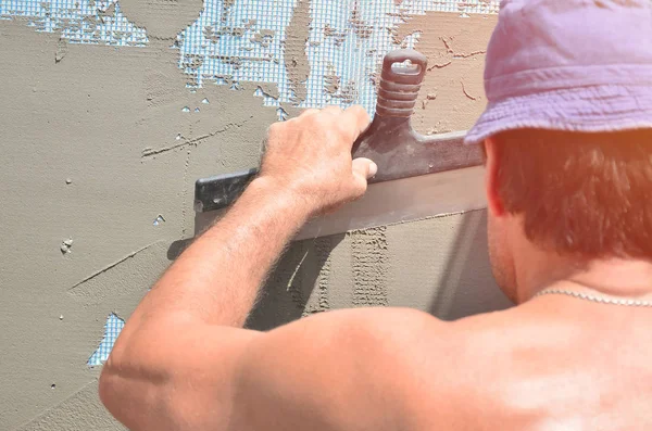 Fifty years old manual worker with wall plastering tools renovating house. Plasterer renovating walls and corners with spatula and plaster. Wall mash installation. Construction finishing works — Stock Image Fifty Years Old Manual Worker Wall Plastering Tools Renovating House Stock Photo