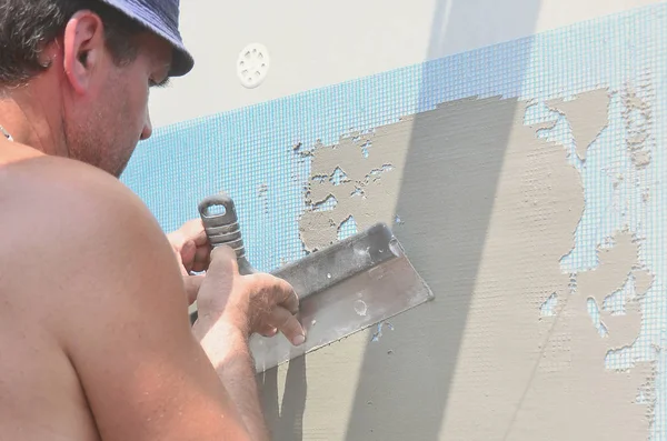Fifty years old manual worker with wall plastering tools renovating house. Plasterer renovating walls and corners with spatula and plaster. Wall mash installation. Construction finishing works — Stock Image Fifty Years Old Manual Worker Wall Plastering Tools Renovating House Stock Photo