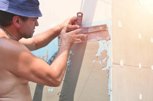 Fifty years old manual worker with wall plastering tools renovating house. Plasterer renovating walls and corners with spatula and plaster. Wall mash installation. Construction finishing works — Stock Image Fifty Years Old Manual Worker Wall Plastering Tools Renovating House Royalty Free Stock Images
