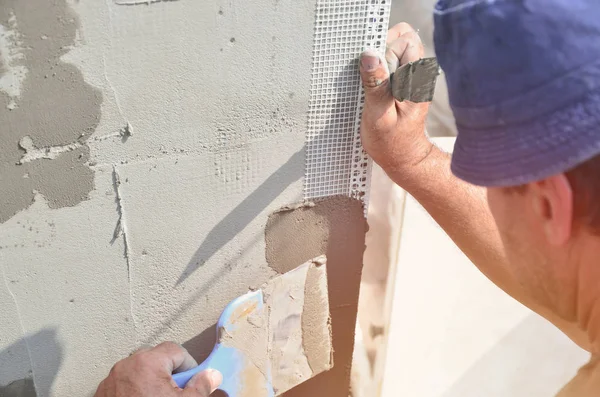 Fifty years old manual worker with wall plastering tools renovating house. Plasterer renovating walls and corners with spatula and plaster. Wall mash installation. Construction finishing works — Stock Image Fifty Years Old Manual Worker Wall Plastering Tools Renovating House Royalty Free Stock Images