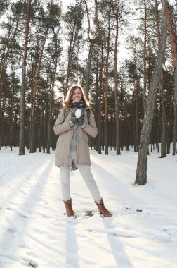 Genç ve neşeli beyaz kız kahverengi kabanlı bir kartopu kışın bir karla kaplı ormanda tutar. Balıkgözü fotoğraf