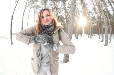 Kahverengi bir ceket genç ve neşeli beyaz kız kış aylarında karla kaplı bir ormandaki bir kartopu sculpts. Açık havada kar oyunlar. Balıkgözü fotoğraf