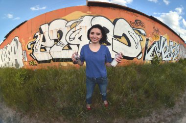 Siyah saçlı ve piercing ile duygusal bir genç kız portresi. Sprey boya... kutularını graffiti duvar arka plan üzerinde elinde bir kızla bir geniş açı fotoğraf. Bir balıkgözü lens modern bir portresi