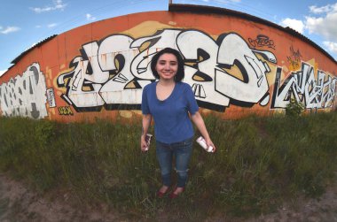 Siyah saçlı ve piercing ile duygusal bir genç kız portresi. Sprey boya... kutularını graffiti duvar arka plan üzerinde elinde bir kızla bir geniş açı fotoğraf. Bir balıkgözü lens modern bir portresi
