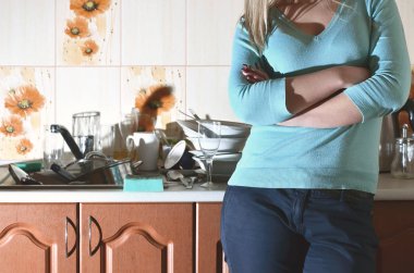 Fragment of the female body at the kitchen counter, filled with a lot of unwashed dishes. The girl is tired of coping with the daily duty of washing dishes. Problems of family life clipart
