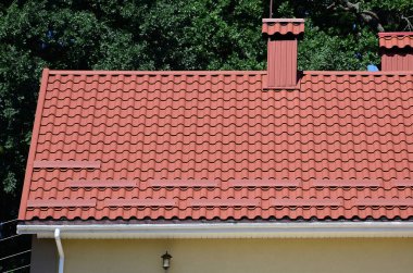Yüksek kaliteli kırmızı metal kiremit çatı bir evin yeşil ağaçlar arka plan