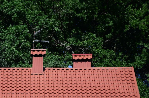 高品质红色金属瓦片房子的屋顶对绿色树背景 — 图库照片