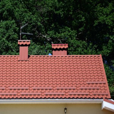 Yüksek kaliteli kırmızı metal kiremit çatı bir evin yeşil ağaçlar arka plan