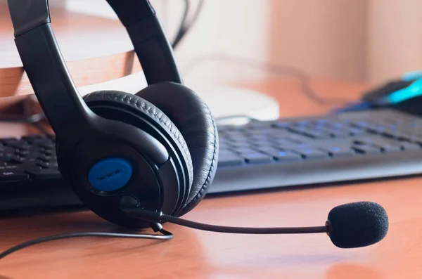 Big black headphones lie on the wooden desktop of the sound designer. Workplace for music creator. Selective focus