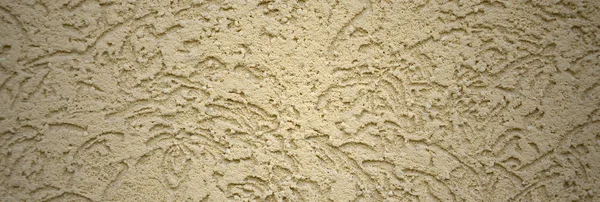 The texture of the beige decorative plaster in bark beetle style. Russian variation of decorating facade walls
