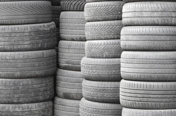 Old used tires stacked with high piles in secondary car parts shop garage close up