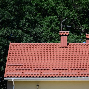 Yüksek kaliteli kırmızı metal kiremit çatı bir evin yeşil ağaçlar arka plan