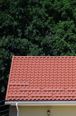 Yüksek kaliteli kırmızı metal kiremit çatı bir evin yeşil ağaçlar arka plan